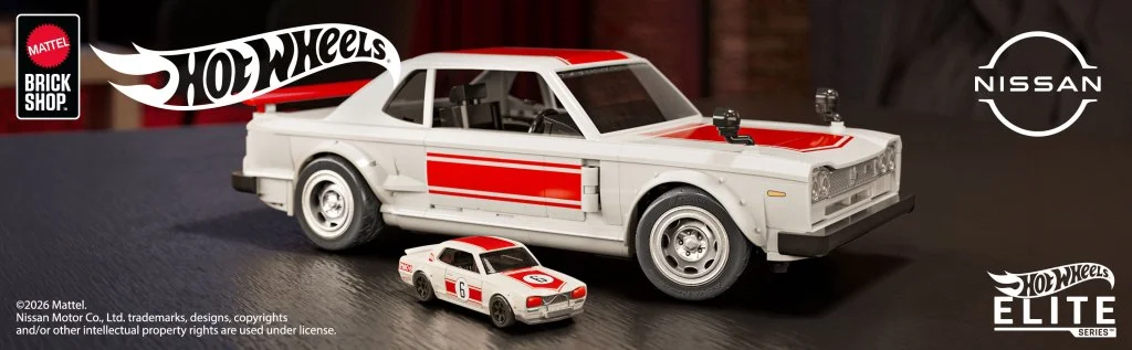 A display of two Hot Wheels cars featuring a larger white and red Nissan model alongside a smaller version. The background includes branding for Mattel and Nissan, emphasizing the Elite Series.