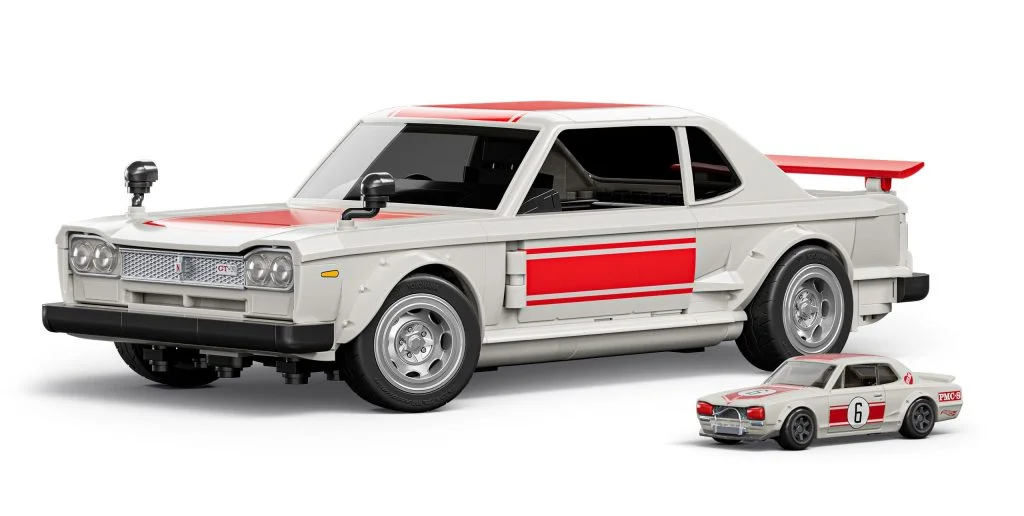 A large scale model of a race car in white with red accents, featuring details like dual side mirrors and a rear spoiler, next to a smaller version of the same car.